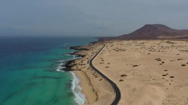 İnsansız hava aracı görüntüsü, asfalt yol ile Corralejo Doğal Parkı 'nın engin kumulları arasındaki zıtlığı gösteriyor..