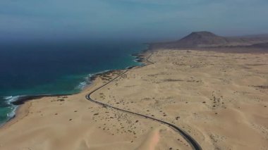 Corralejo 'da sonsuz kum tepeleriyle çevrili ıssız bir yolun yüksek açılı insansız hava aracı görüntüleri özgürlük, seyahat ve doğal güzelliği vurguluyor..