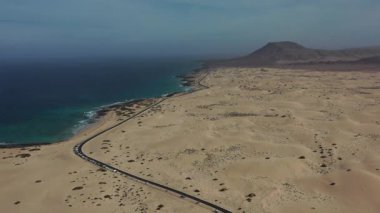 İnsansız hava aracı görüntüsü, asfalt yol ile Corralejo Doğal Parkı 'nın engin kumulları arasındaki zıtlığı gösteriyor..