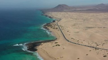 İnsansız hava aracı görüntüsü, asfalt yol ile Corralejo Doğal Parkı 'nın engin kumulları arasındaki zıtlığı gösteriyor..