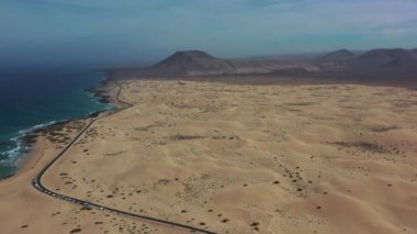 Corralejo 'da sonsuz kum tepeleriyle çevrili ıssız bir yolun yüksek açılı insansız hava aracı görüntüleri özgürlük, seyahat ve doğal güzelliği vurguluyor..