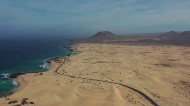 Parlak ve güneşli bir günde çekilen Corralejo Fuerteventura 'nın altın kum tepelerini kesen dolambaçlı bir yolun çarpıcı hava görüntüleri..