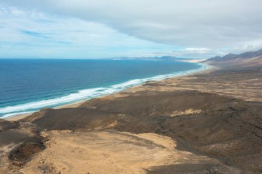 Kahve Sahili 'nin manzarası bulutlu bir gökyüzünün altında sisli dağlarla çevrili..