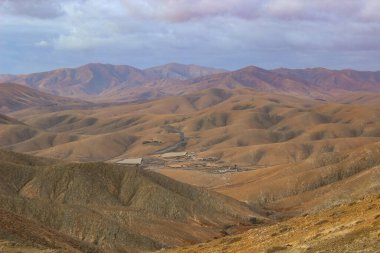 İnsansız hava aracı, adanın eşsiz volkanik oluşumları ve toprak tonlarıyla harmanlanmış, hareketli bir yol görüntüsü..