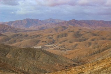 İnsansız hava aracı, adanın eşsiz volkanik oluşumları ve toprak tonlarıyla harmanlanmış, hareketli bir yol görüntüsü..