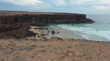 Esquinzo Sahili 'nin hava sahili Fuerteventura, bulutlu gökyüzü ve sakin okyanusla.