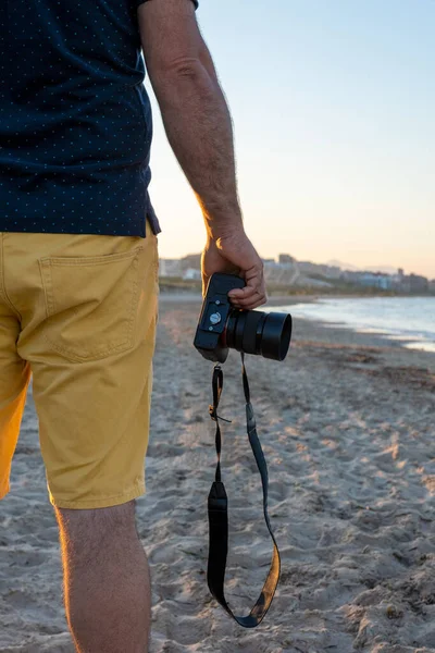 Kumsalda kameralı bir adam tatilde.