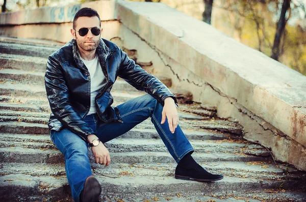 Deri ceket ve güneş gözlüğü dışarı giyen tutum ile seksi adam