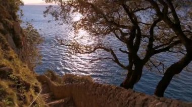 Güneşin doğuşuyla birlikte, uçurumun ortasındaki kaldırımlı bir merdivenden denizin büyüleyici manzarası.