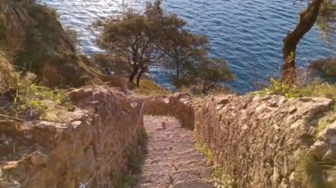 Güneşin doğuşuyla birlikte, uçurumun ortasındaki kaldırımlı bir merdivenden denizin büyüleyici manzarası.