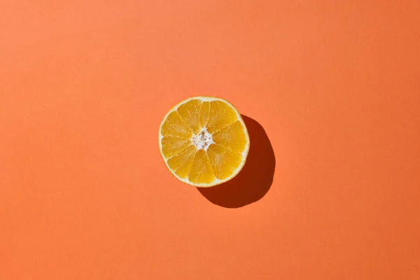 Fresh orange cut in half on an orange background. Minimalist concept. Copy space