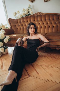 Klasik iç mekanda zarif bir kadın yerde dinleniyor.