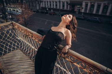 Siyahlı dramatik kadın şehir balkonundan eğiliyor.