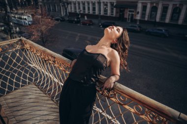 Kadın kafasını şehir zeminiyle balkona yaslıyor.