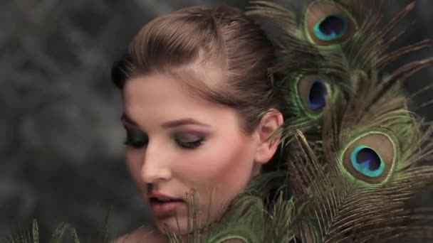 Дівчина з кольоровим макіяжем і пером для павичів — стокове відео