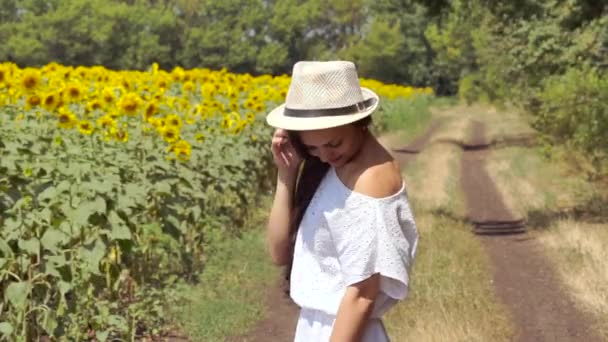 Vrouw loopt over de weg in de buurt van een veld met zonnebloemen — Stockvideo