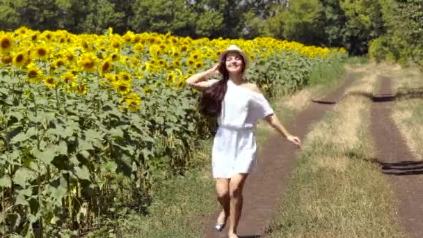 Vrouw loopt over de weg in de buurt van een veld met zonnebloemen — Stockvideo