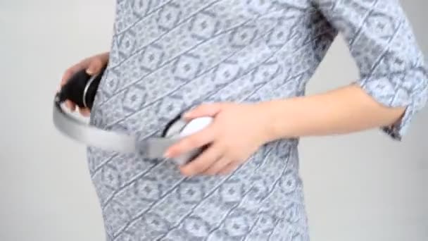 Femme enceinte avec écouteurs sur le ventre — Video