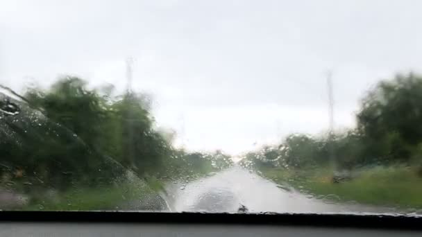 Идёт дождь. капли дождя падают на стекло автомобиля — стоковое видео