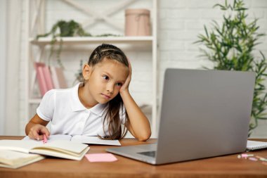 Küçük kız çevrimiçi çalışmak için laptop kullanıyor.