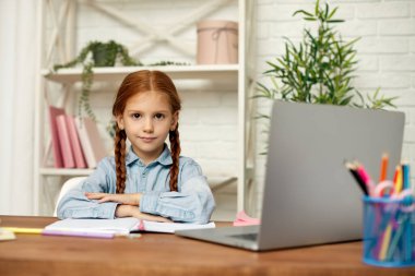 Küçük kız çevrimiçi çalışmak için laptop kullanıyor.