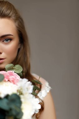 Çiçek buketi olan genç ve güzel bir gelin.