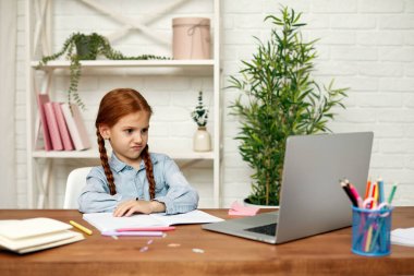 Küçük kız çevrimiçi çalışmak için laptop kullanıyor.