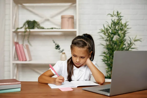 Маленькая девочка, использующая ноутбук для онлайн-уроков дома — стоковое фото