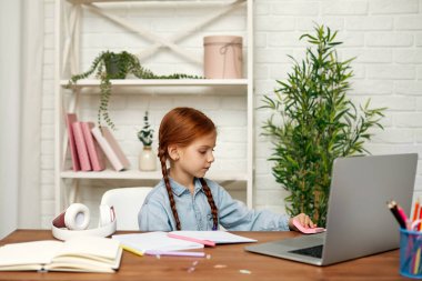 Küçük kız çevrimiçi çalışmak için laptop kullanıyor.