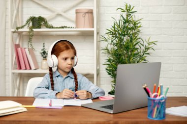 Küçük kız çevrimiçi çalışmak için laptop kullanıyor.