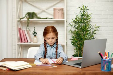 Küçük kız çevrimiçi çalışmak için laptop kullanıyor.