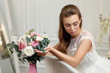 Çiçek buketi olan genç ve güzel bir gelin.