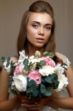 Çiçek buketi olan genç ve güzel bir gelin.