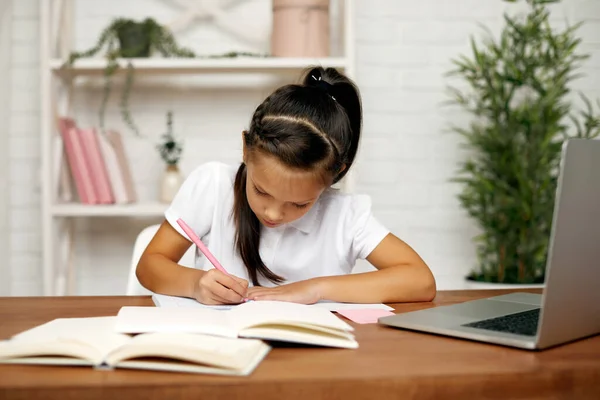 Kisgyermek lány használ laptop online leckét otthon — Stock Fotó