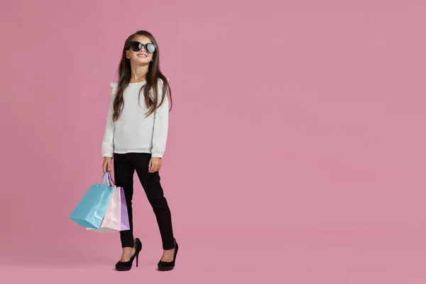 Menina em óculos de sol está segurando sacos de compras — Fotografia de Stock
