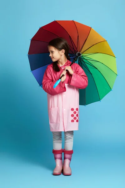 Menina com guarda-chuva multicolorido em capa de chuva rosa — Fotografia de Stock