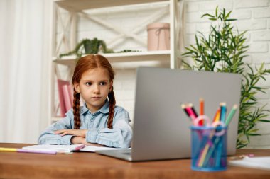 Küçük kız çevrimiçi çalışmak için laptop kullanıyor.