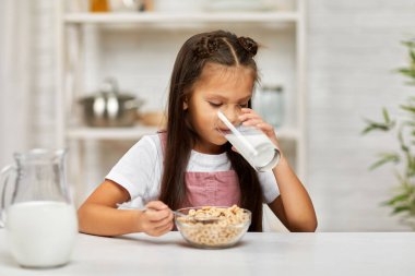 Küçük tatlı kız kahvaltı yapıyor: mısır gevreği ve süt.