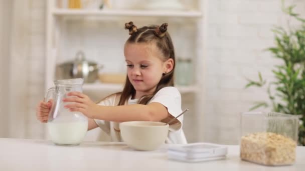 Дитина п'є молоко в миску з зернових на кухні . — стокове відео
