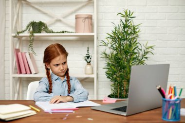 Küçük kız çevrimiçi çalışmak için laptop kullanıyor.