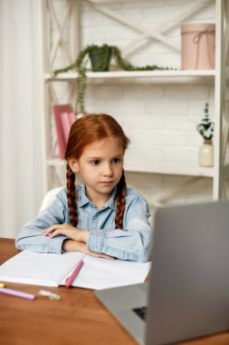 Küçük kız çevrimiçi çalışmak için laptop kullanıyor.