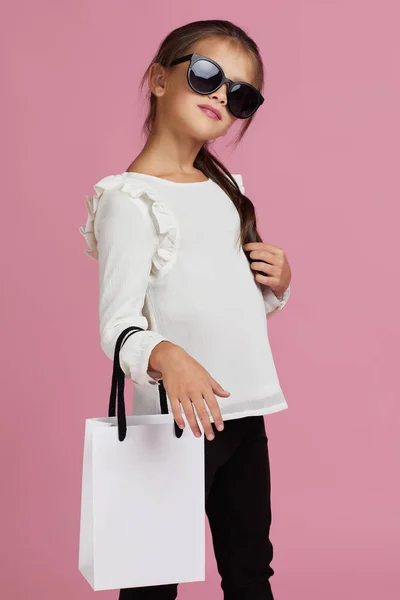 Dítě dívka v slunečních brýlích drží nákupní tašky — Stock fotografie