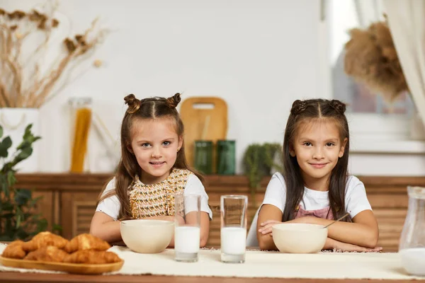 Маленькі дівчатка, які снідають - свіжі смачні круасани та молоко — стокове фото