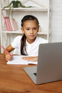 Küçük kız evde online ders için dizüstü bilgisayar kullanıyor.