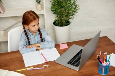 Küçük kız çevrimiçi çalışmak için laptop kullanıyor.