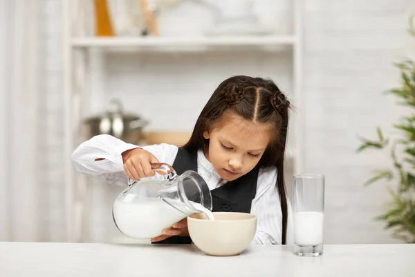 Усміхнена мила дівчинка їсть сніданок: крупа з молоком — стокове фото