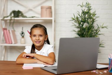 Küçük kız evde online ders için dizüstü bilgisayar kullanıyor.