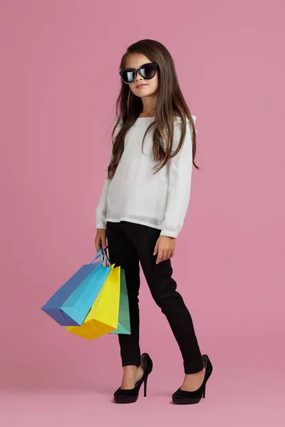선글라스를 낀 소녀가 쇼핑백을 들고 있다 — 스톡 사진