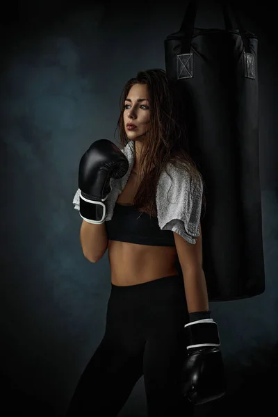 sporty woman in black boxing gloves in studio background
