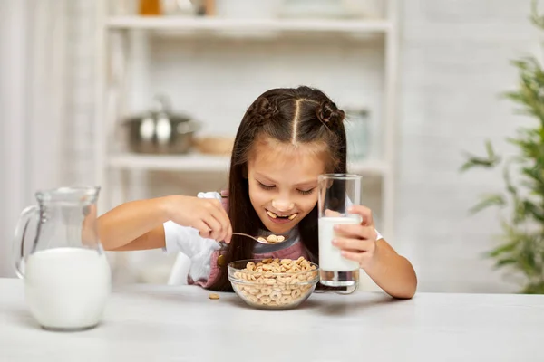 Мила дівчинка їсть сніданок: крупа з молоком — стокове фото